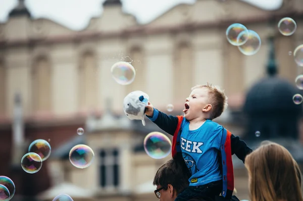 Boy sitting on dad\'s shoulders and touched giant bubbles