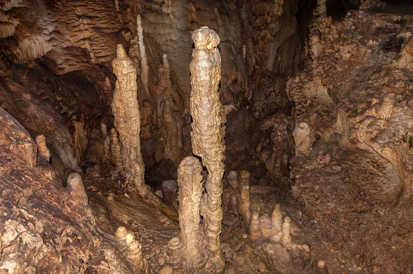 High mineral stalagmites inside the dark cave.