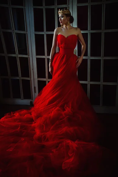 Beautiful girl in long red dress and in royal crown