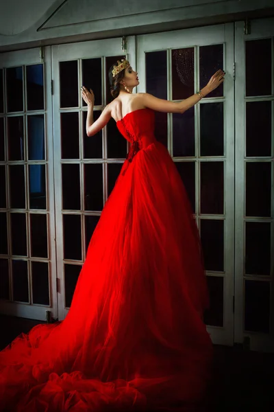 Beautiful girl in long red dress and in royal crown