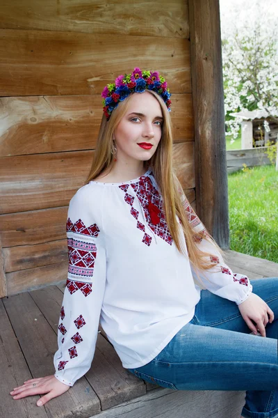 Young beautiful blonde girl with long hair in Ukrainian blouse and in a wreath in outdoor ethnic village Pirogovo in Kiev Ukraine