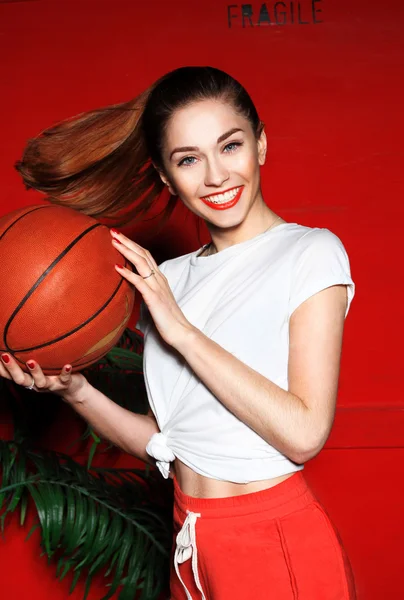 Sports girl in red chert and a white T-shirt standing on red box or container ,  her palm branches in their hands her basketball athletic body,  perfect photo for the cover of the magazine, sports ads