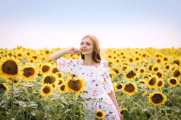 Beautiful sweet sexy girl in a white dress walking on a field of sunflowers , smiling  a beautiful smile,cheerful girl,style, lifestyle , ideal for advertising and photo sun  shines bright and juicy