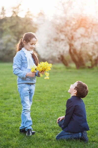 Boy gave flowers to girl and stood in front of her on his knee