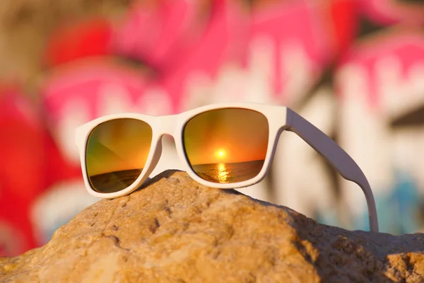 Sunglasses lying on rock on background of graffiti
