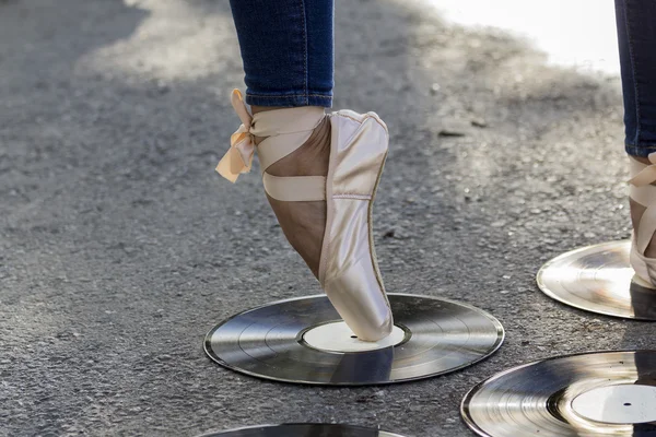 Foot girls in Ballet shoes stands on a vinyl disk.