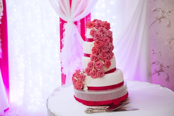 Big white wedding cake with pink roses on a table