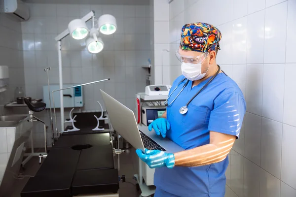 Doctor with laptop and medical tools in operating room at the hospital