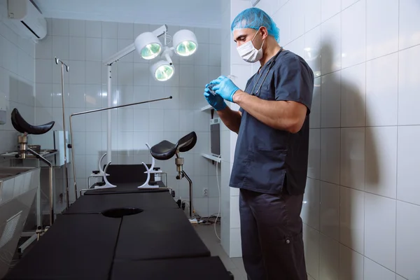 Young man surgeon takes on his protective glasses after operation in hospital.