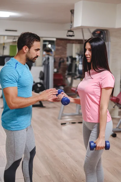 Male trainer seriously train girl biceps with dumbbells