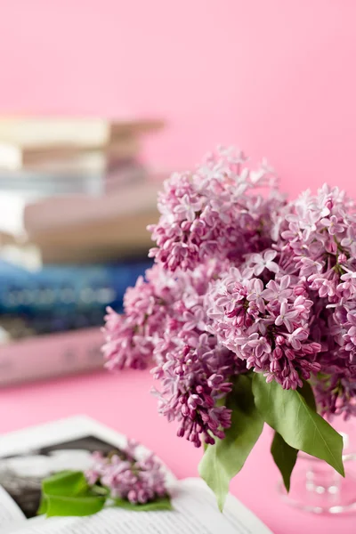 Bouquet of lilac and books on pink background
