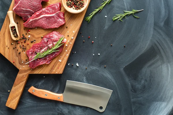 Fresh raw meat on chopping board with knife. top-view