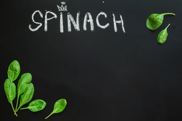 Green spinach leaves on a black chalkboard with text