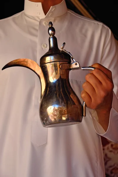 A Saudi man holding a Saudi Arabian teapot