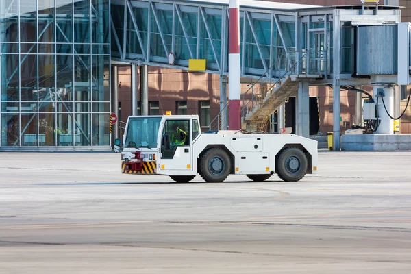 Airplane tow truck near passenger boarding bridge