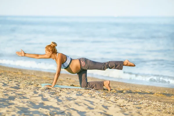 Pregnant woman doing yoga on the beach. Soft light. Beautiful girl with a swimsuit. Sea. She relax yoga.