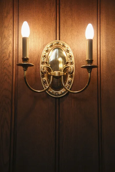 Vintage old wall candle lamp illuminates a dark room.