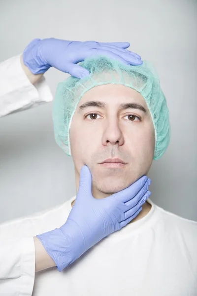 Doctor hands holding head of patient in a medical cap