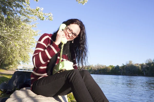 Woman close to the river talking by the phone laughing friendly
