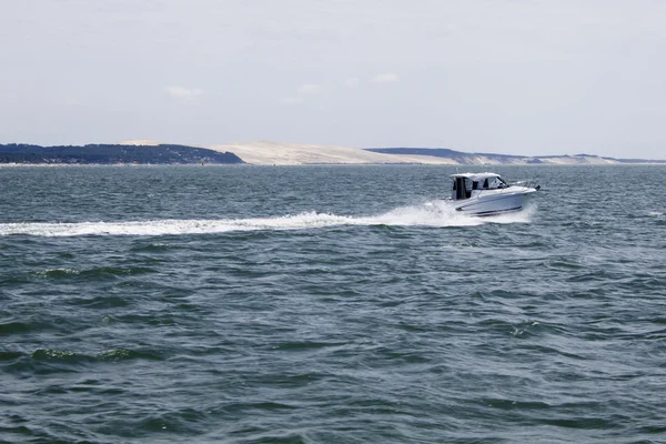 Motor boat speeding in front of Pilat dune in France