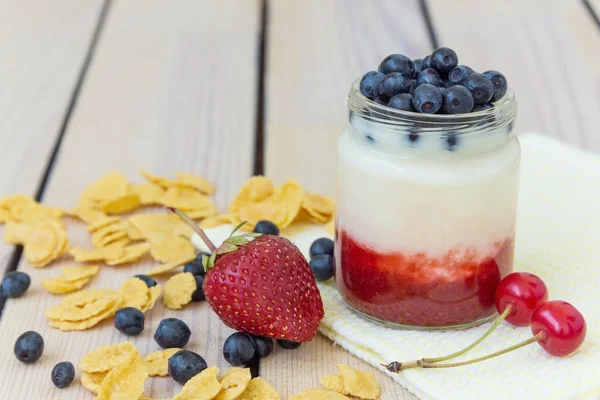 Yogurt with strawberry jam cherries and blueberries and corn flakes