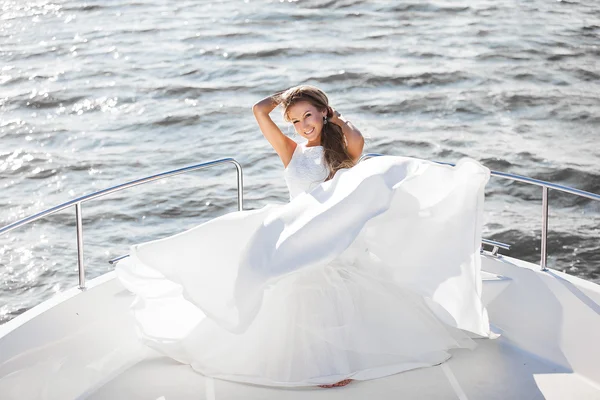 Happy bride in a white wedding dress on a yacht sailing wind evolve her hair and dress