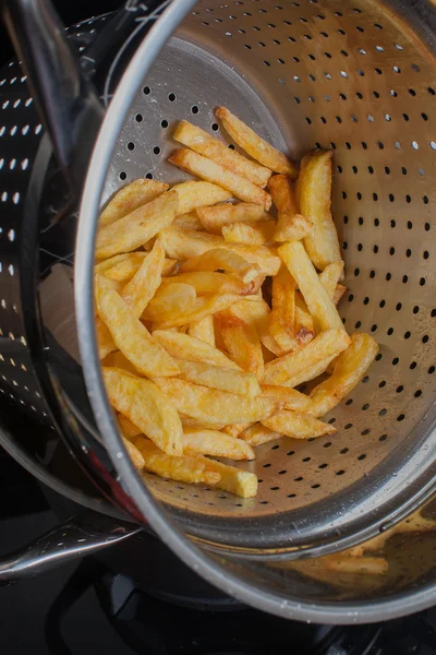 A lot of delicious french fries cooked at home   in hot fat in a deep fryeron