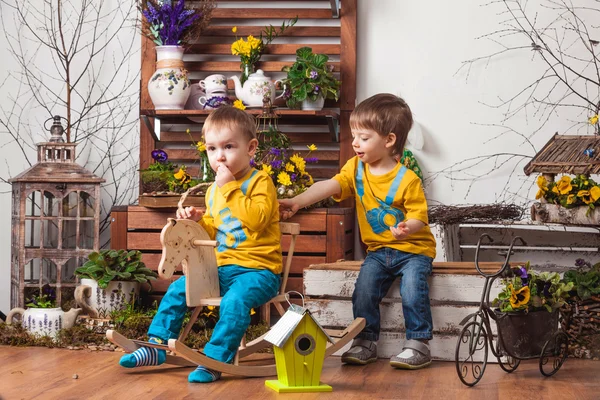 Children on the background of spring decor in yellow T-shirts , flower meadow .
