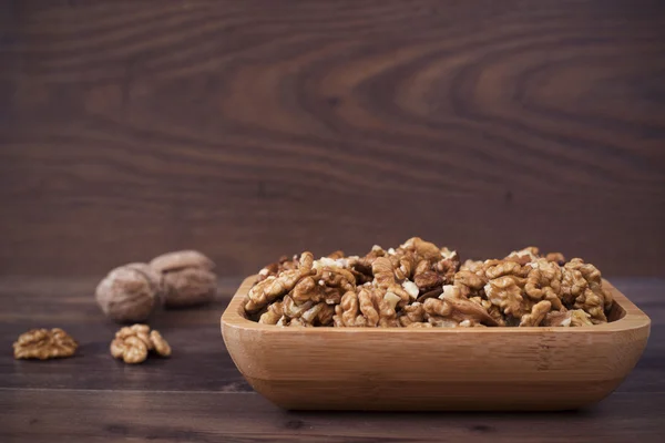 Bamboo bowl with walnuts on a wooden background