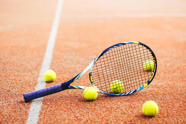 Tennis racket with many balls on clay cour