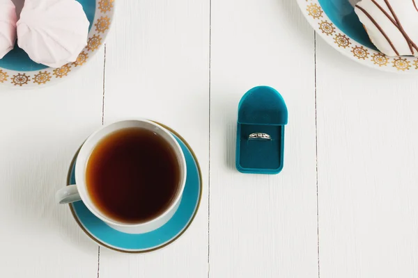 Tea with sweets on a white background whith ring. An offer of marriage, box which give ring