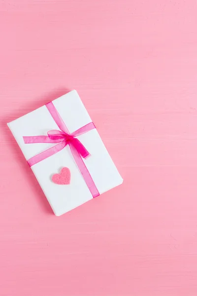 Packed gift with small heart on a pink background. Selective focus, top view, macro, toned image, film effect