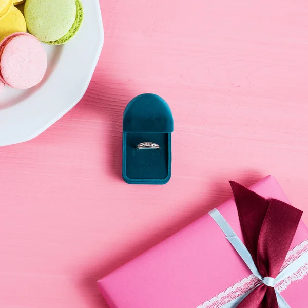 Offer of marriage, box which give ring macaroon and gift on pink background. . Selective focus, top view, macro, toned image, film effect