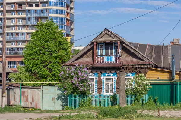 Log (wood) house under construction on the background of high-rise buildings. Street Iaroslavskaia, Cheboksary, Chuvash Republic, Russia. 05/18/2016 Horizontal frame.