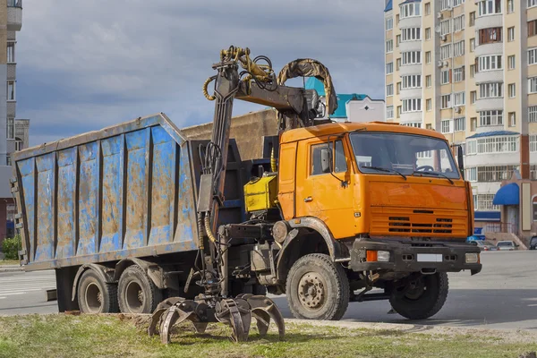 Old truck for transportation and loading of scrap in the city moved the tongs to grip scrap iron.