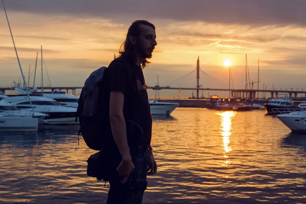 Guy with long hair in silhouette standing on the beach