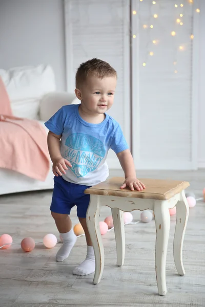 Little boy playing with chair in decored room