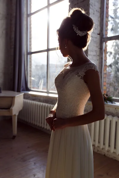 Silhouette of beautiful bride standing near window