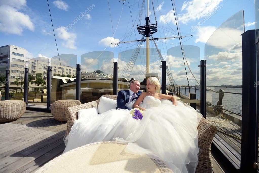 Couple de mariage sur yacht étreignant les uns les autres. Belle jeune fille en robe blanche. Homme en costume. Mariée beauté avec groom.