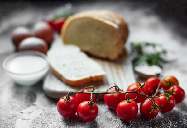 Ingredients for the preparation of bakery products. Bread, flour, eggs and cherry tomatoes.