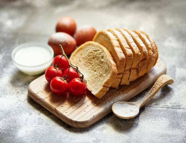 Ingredients for the preparation of bakery products. Bread, flour, eggs and cherry tomatoes.