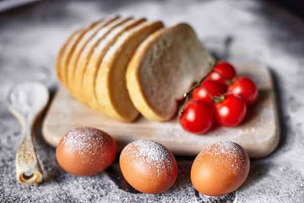 Ingredients for the preparation of bakery products. Bread, flour, eggs and cherry tomatoes.