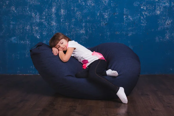 Cushioned furniture. A child with toys and books on a chair bag