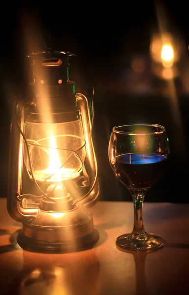 Glass of wine and kerosene lamp in the evening