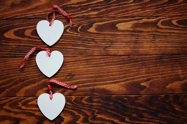 Valentines day background. Three white wooden hearts on wooden background, copy space