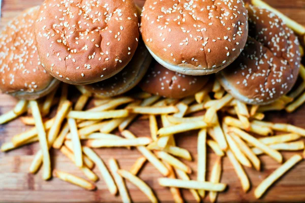 Burger buns with french fries on wooden background