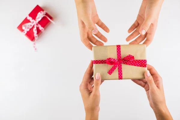 Closeup of hands giving gifts to each other on white background