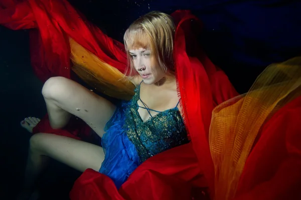 Beautiful girl confused in the tissues underwater. Portrait. Horizontal orientation.