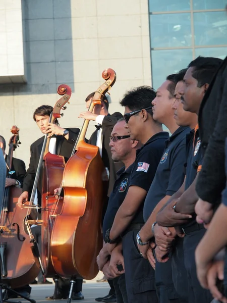 Requiem for the victims of flight MH17. Malaysian employees on the background of a contrabass players