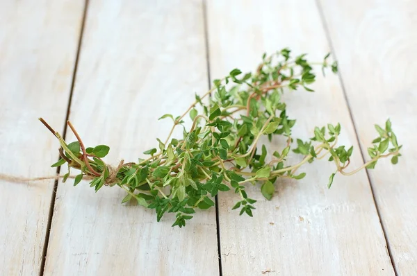 Fresh green herb thyme on white wooden background